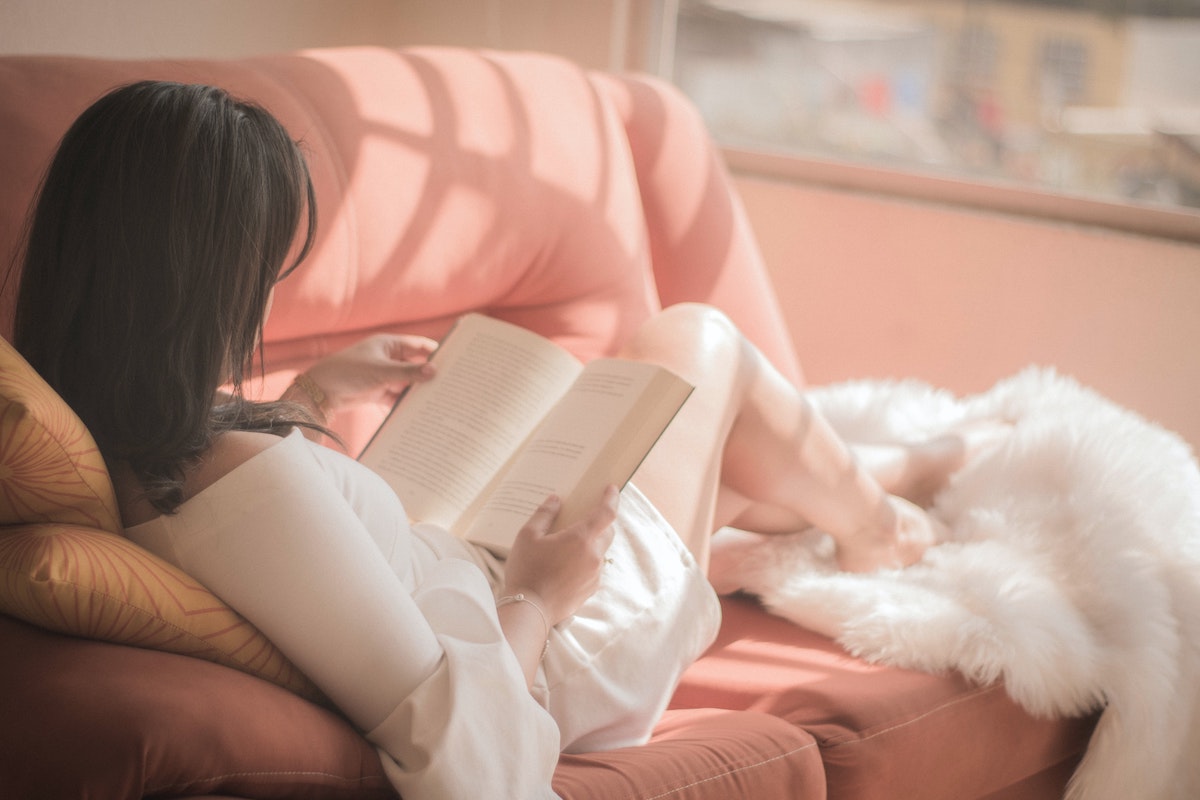 femme lit un livre sur canapé